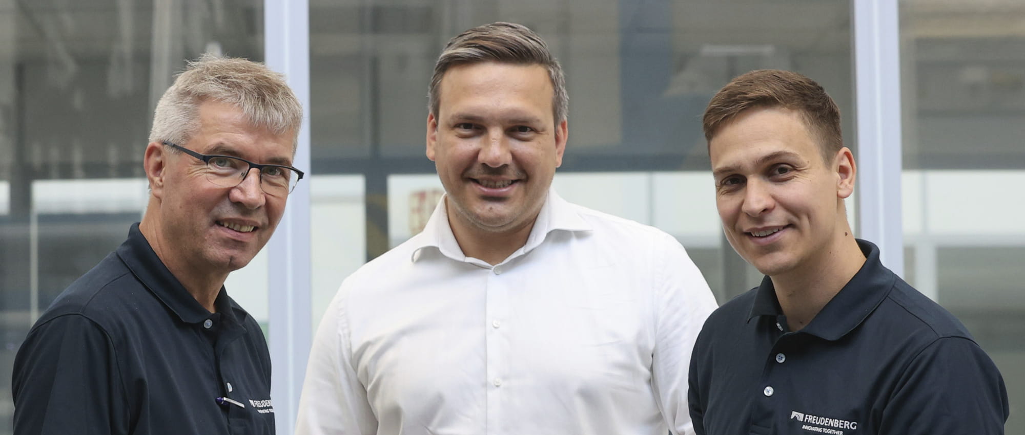 Three men look into the camera smiling.