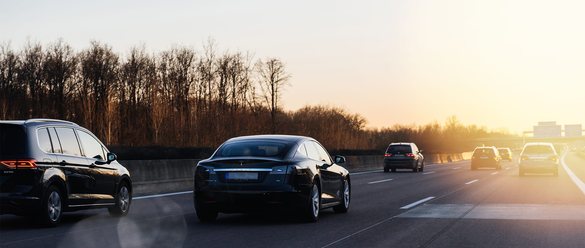 Cars driving on a highway during sunset.