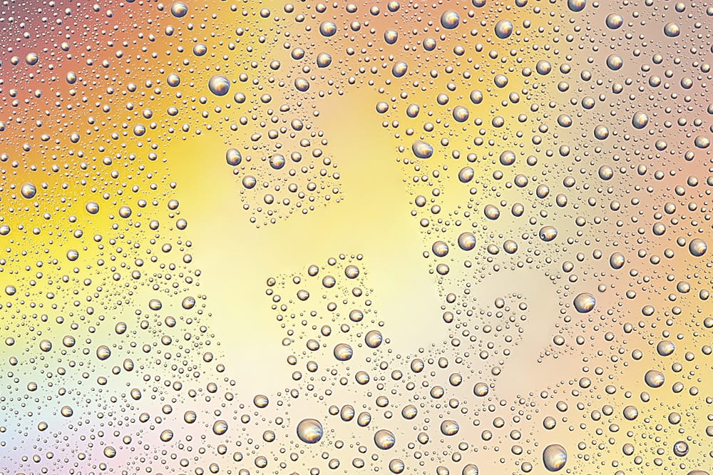 Rainbow-colored background on which water drops are depicted, leaving an area that results in the lettering H2.